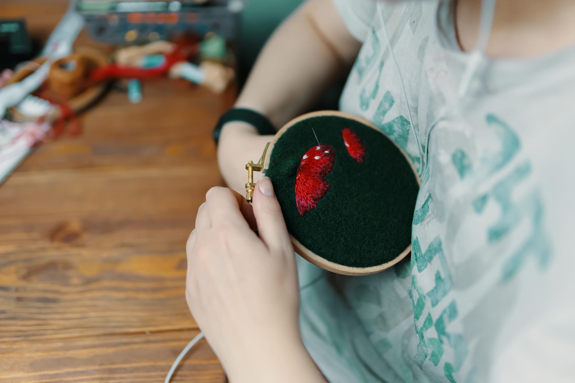 Student stitching detailed floral motif